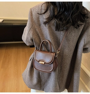 Detail view of a vintage dark brown saddle bag with golden metal buckle on a shoulder strap