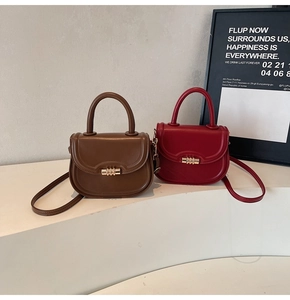 Detail of saddle bags in brown and wine red with gold cylindrical twist locks