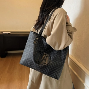 Sac fourre-tout rétro noir avec imprimé lettres M et bandoulière porté par un mannequin