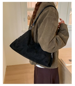 Détail d'un sac hobo vintage en daim noir porté à l'épaule avec bandoulière réglable
