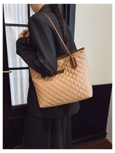 Quilted khaki tote bag with dark brown trim shown on model in a professional office setting