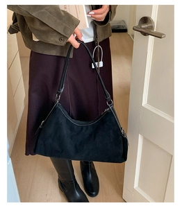 Détail du sac hobo en daim noir minimaliste avec surpiqûres blanches contrastées