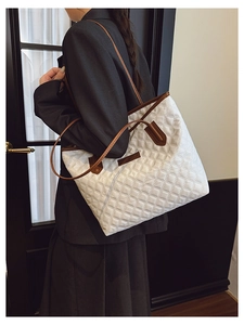Detail of white quilted tote bag with brown leather handles worn by a model