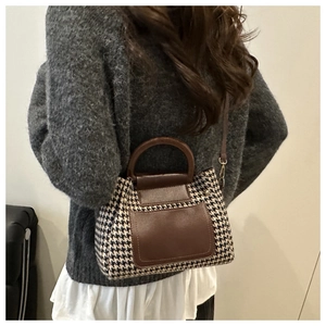 Detail showing contrast houndstooth pattern and brown leather stitching on Boston bag