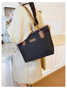 Detail of black quilted tote bag featuring a Fashion & Bags metal plaque and slim brown straps