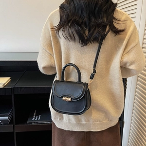 Minimalist black saddle bag with gold metal clasp and top handle for women