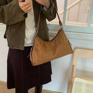 Brown faux suede underarm bag with minimalist half-moon shape and shoulder strap