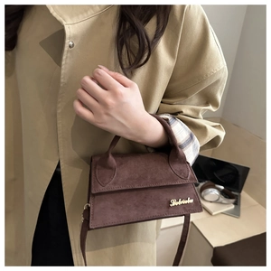 Detailed shot of a brown suede small square crossbody bag with gold logo on beige trench coat