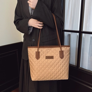 Quilted tote bag in khaki with leather brand tag shown on model in black suit