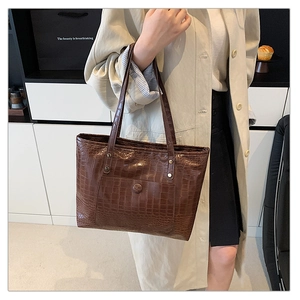 Detail of vintage brown crocodile embossed tote bag with glossy finish and pocket