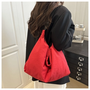 Macro detail of the red large nylon shoulder bag with a stylish black wide strap