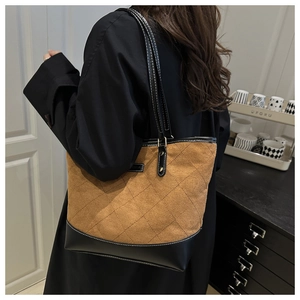 Detail of the oversized quilted tote bag with brown suede and black leather stitching