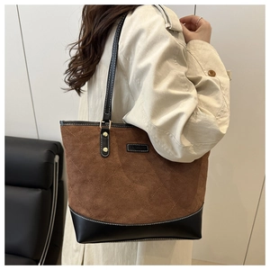 Close-up of quilted suede tote bag with black leather bottom and gold rivet details