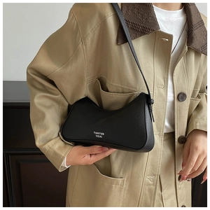 Detail of black pebbled leather underarm bag with white logo on a khaki jacket outfit