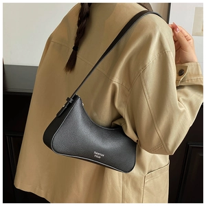 Close-up of black lychee grain leather hobo bag worn over shoulder with beige coat