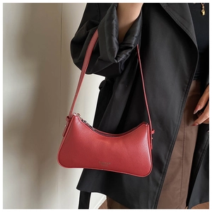 Close-up of red lychee grain leather underarm bag with gold logo on black blazer outfit