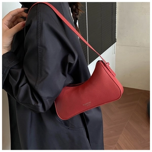 Close-up of red lychee pattern underarm bag featuring a gold logo on black coat