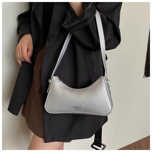 Silver crescent hobo bag with litchi texture and metallic finish on a black blazer
