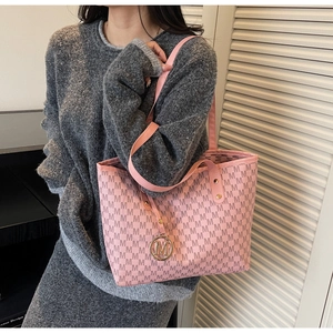 Detail of pink monogram tote bag with golden M charm and textured faux leather finish