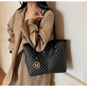 Detail of black tote bag with gray M-letter print and golden M-shaped metal charm