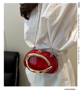 Red patent leather oval crossbody bag with gold chain strap and metal handle detail