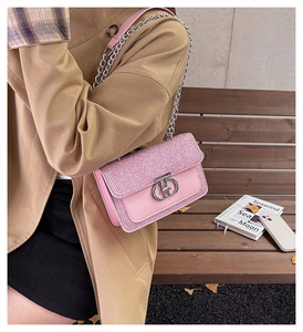 Close-up of pink sequined flap bag with silver ring buckle and leather chain strap