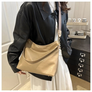 Detail of khaki PU leather tote bag featuring a textured woven shoulder strap and metal feet