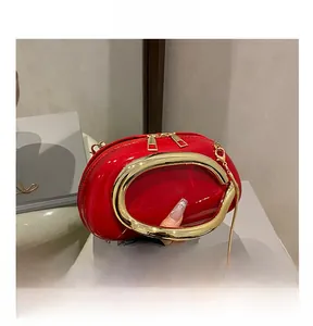 Macro detail of red patent leather mini bag with gold chain and unique oval design