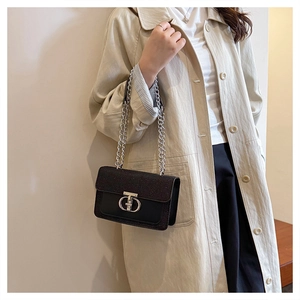 Detail of black sequined crossbody bag with silver chain strap and metal clasp on model