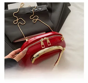 Detailed close-up of red patent leather handbag with gold zipper and chain strap