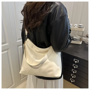 Model showing large creamy white hobo bag with wide shoulder strap in lifestyle setting