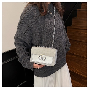 Detail of silver sequined crossbody bag with metallic chain strap on model in grey sweater
