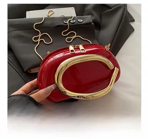 Detail of red patent leather pillow bag with large gold handle and snake chain