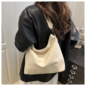 Detail of a large cream hobo bag with textured faux leather and gold hardware