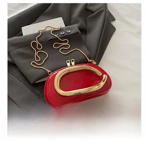 Macro detail of red patent leather purse featuring an oval shape and gold C-shaped handle