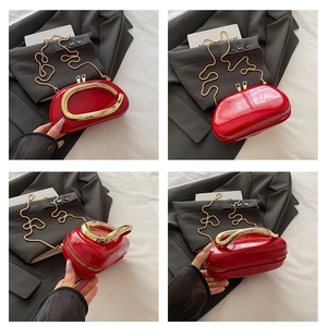 Detail of red patent leather handbag featuring unique gold ring handle and metal chain