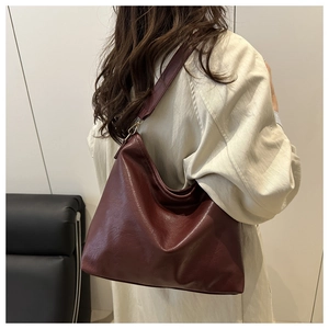 Detail view of large burgundy hobo shoulder bag with smooth synthetic leather and gold buckle