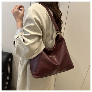 Detail of dark wine red large tote bag showing leather texture and wide shoulder strap