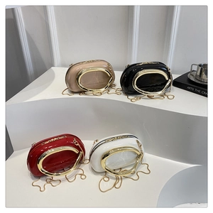 Detail of four glossy patent leather pillow bags with bold oval gold metal handles