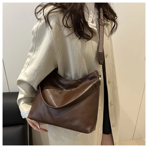 Detail of dark brown tote bag with textured wide strap worn with a beige trench coat