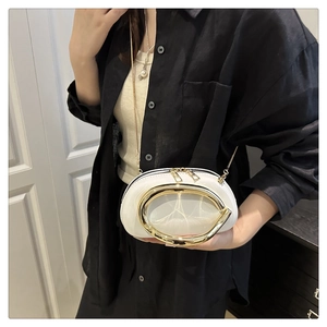 Detail shot of a white crossbody bag with a large gold oval ring and chain strap