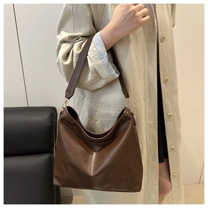 Detail of dark brown leather tote bag with wide strap and golden metal buckle