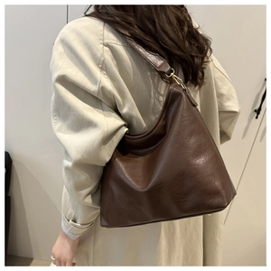 Side view of large coffee brown faux leather tote bag showing crossbody strap and buckle