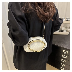 Detailed view of a white mini crossbody bag with a large gold oval ring and chain strap