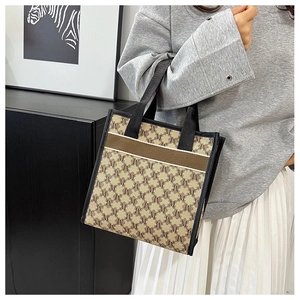 Detail of canvas tote bag with letter M print and brown ribbon on a casual outfit