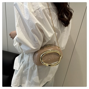 Detail view of stylish beige glossy leather crossbody bag with oversized gold metal ring