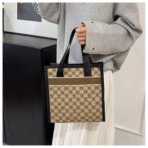 Close-up of monogram pattern tote bag with black fabric handles and stylish M print