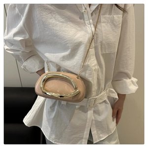 Detail view of the elegant nude leather crossbody bag with a large gold metal ornament