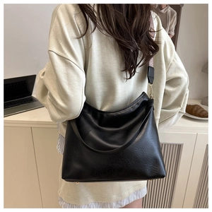 Close-up of black PU leather tote bag with vintage woven shoulder strap and gold hardware