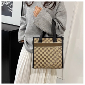 Detail of vintage jacquard tote bag featuring repeating M-pattern and woven handles